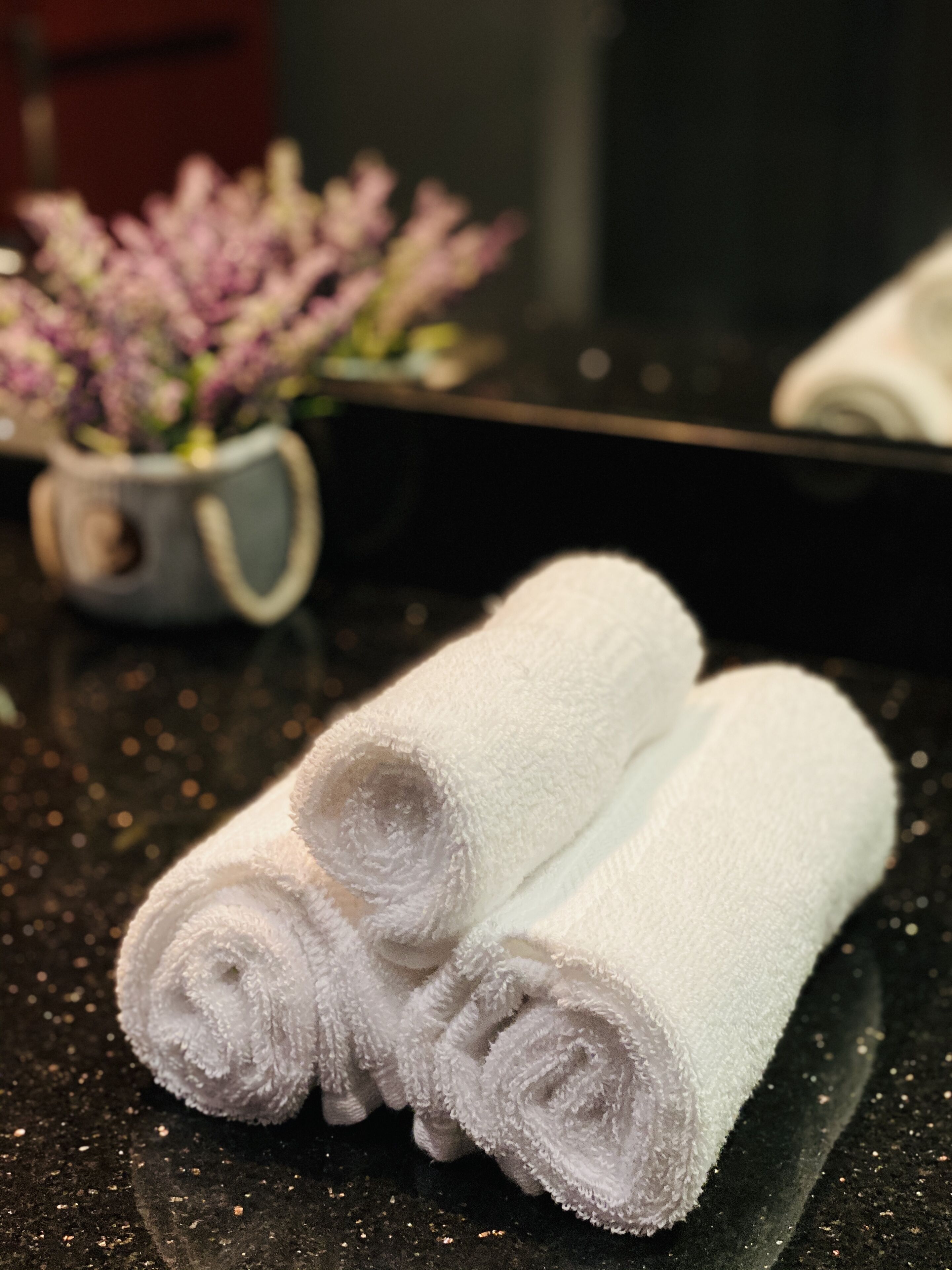 A pair of white towels rolled up on a black countertop.