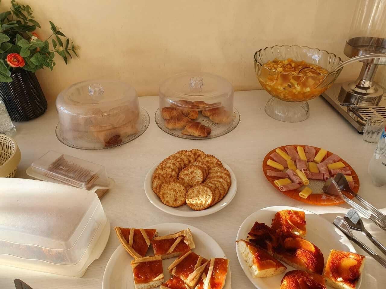 A buffet table with various food items including pastries, a fruit salad, and a pizza.