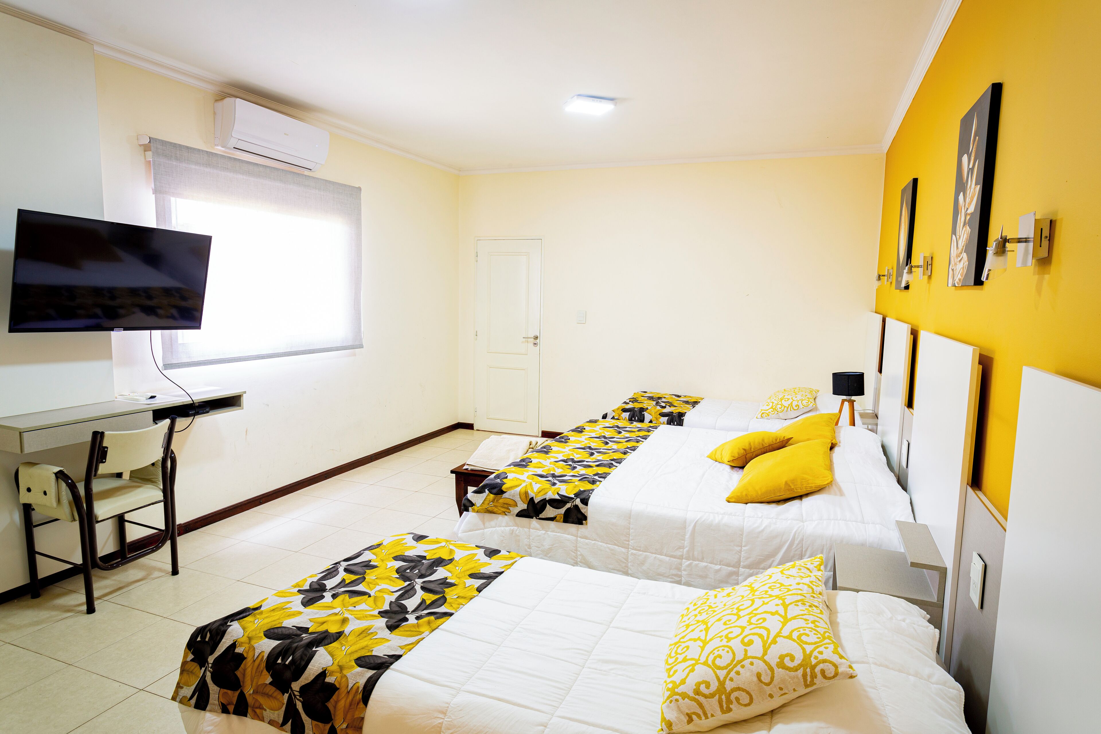 Een hotelkamer met twee bedden, een bureau, een televisie en een airconditioning.