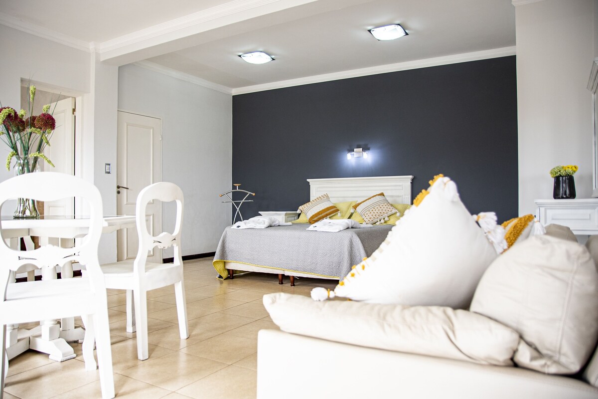 Een moderne slaapkamer met een bed, nachtkastjes en een witte bank.