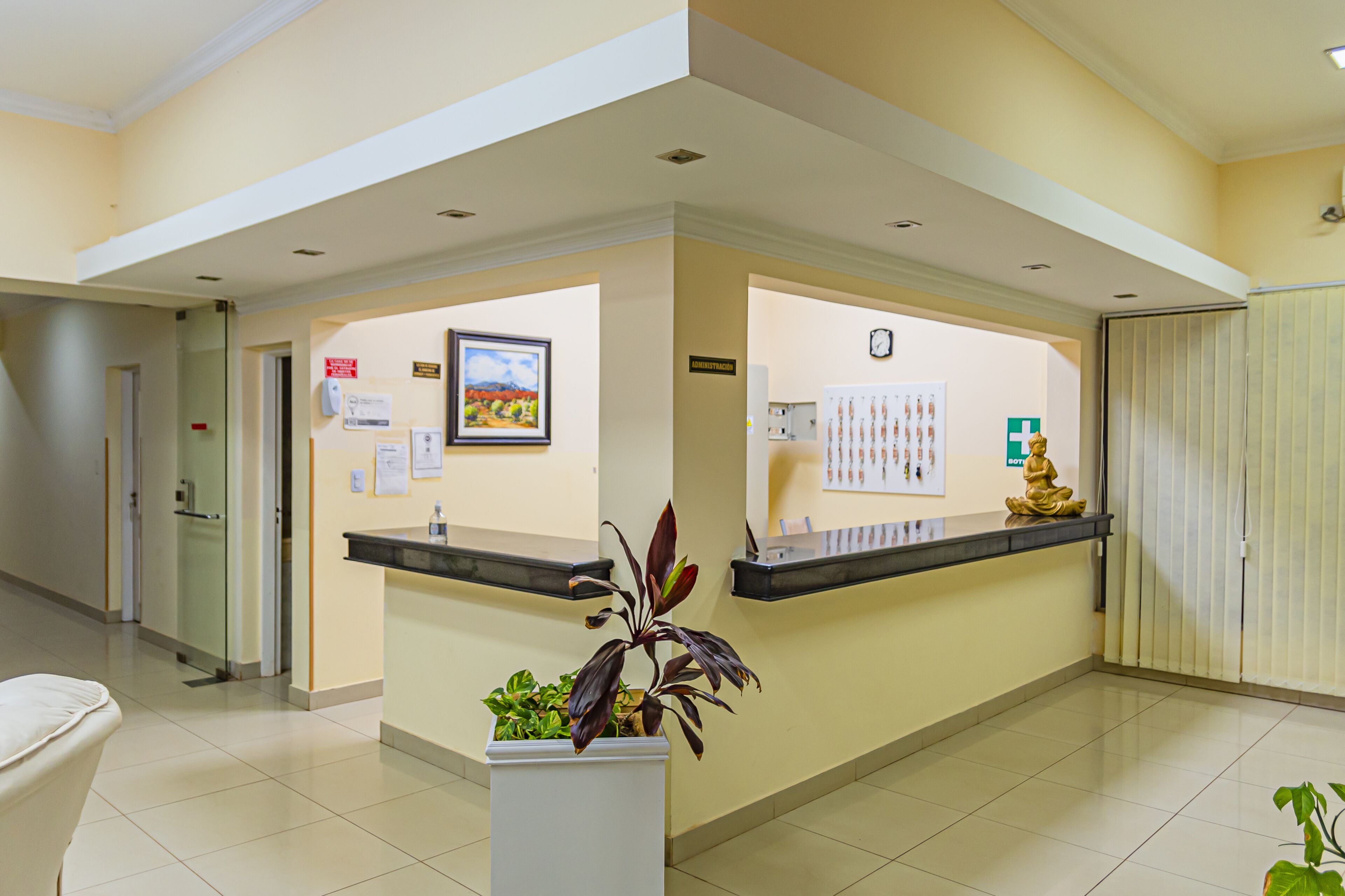 A reception area with a reception desk, a clock, and a Buddha statue.