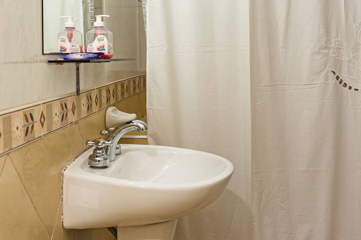 Une salle de bain avec un lavabo, un miroir et un rideau de douche.