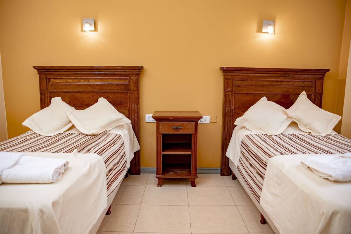 Une chambre d’hôtel avec deux lits, une table de chevet et une prise électrique au mur.