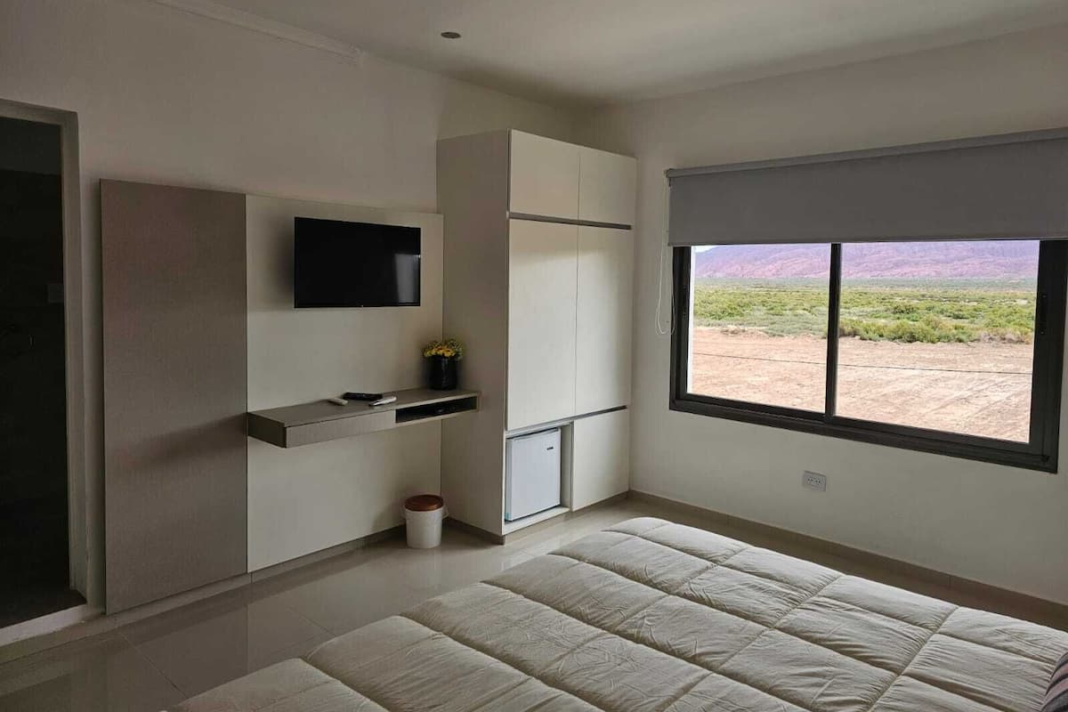 Une chambre moderne dotée d’une grande fenêtre, d’un téléviseur à écran plat, d’un lit et de rangements intégrés.