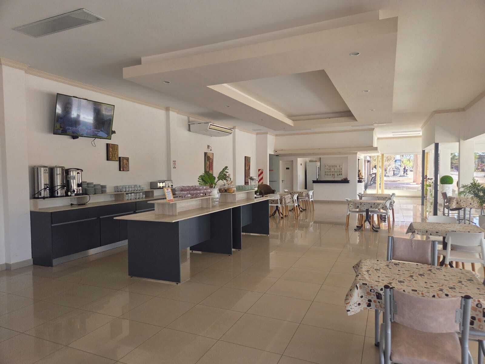 A spacious kitchen with a central island, a flat-screen TV mounted on the wall, and a dining area with chairs and tables.