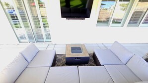 Un área de estar al aire libre y de diseño, con un televisor de pantalla plana sobre una mesa de centro.