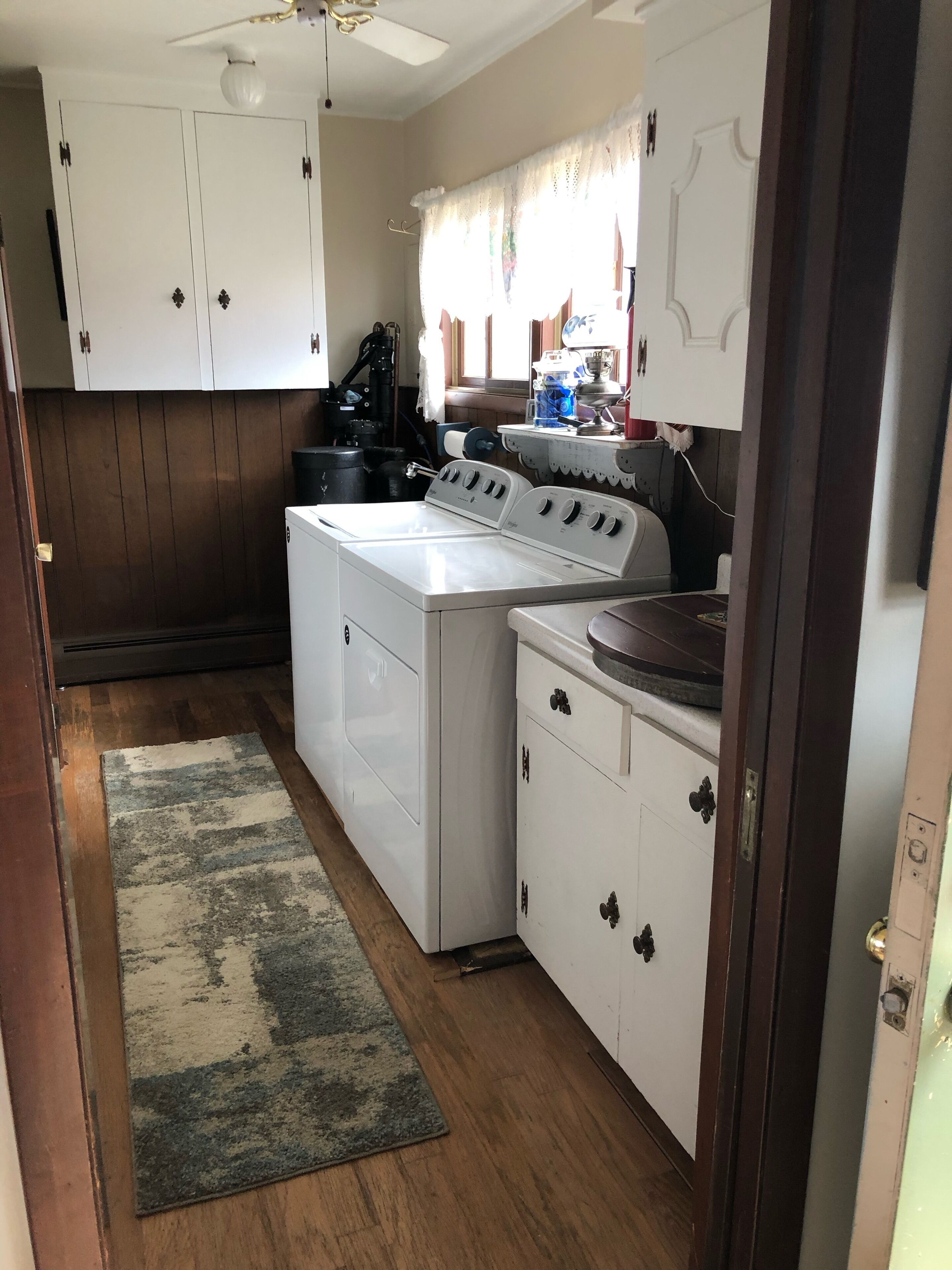 A compact kitchen with white cabinets, a washing machine, and a stove.