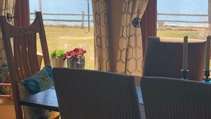 Una habitación con vistas a un lago, una mesa de comedor con sillas y una planta en maceta en el alféizar de la ventana.