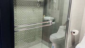 Un baño moderno con cabina de ducha de vidrio, inodoro y lavamanos.