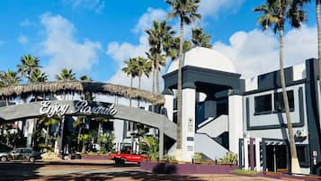 Un edificio moderno con un letrero que dice "Enjoy Rasario" y palmeras al fondo.