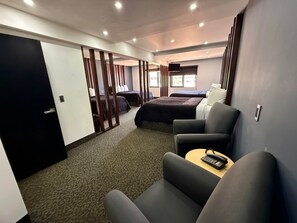 Een hotelkamer met een bed, twee nachtkastjes, een stoel en een bureau met telefoon.