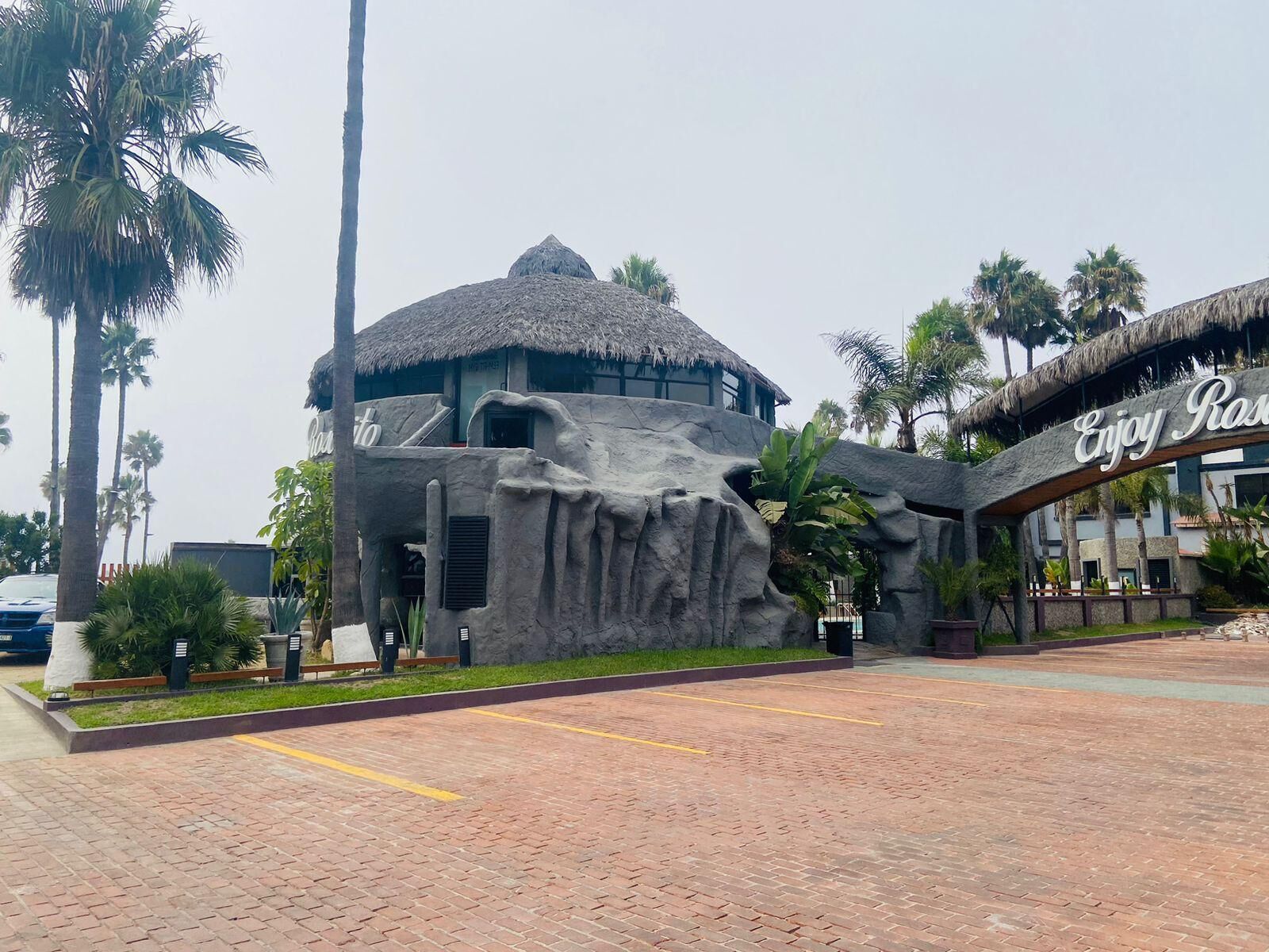 Un resort con una construcción de techo de paja y un letrero que dice 'Disfruta Relájate'.