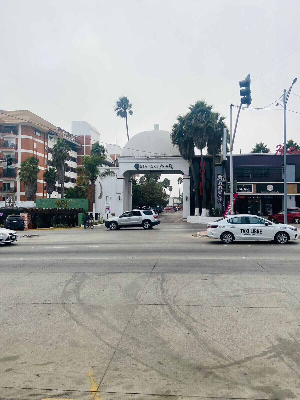 Una intersección con un coche blanco que dice 'TAXI LIBRE' y un edificio con un letrero que pone 'CINTAVOLMAR'.