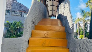Una escalera con una estructura de techo de paja en la parte superior, que lleva a un edificio con techo de paja.
