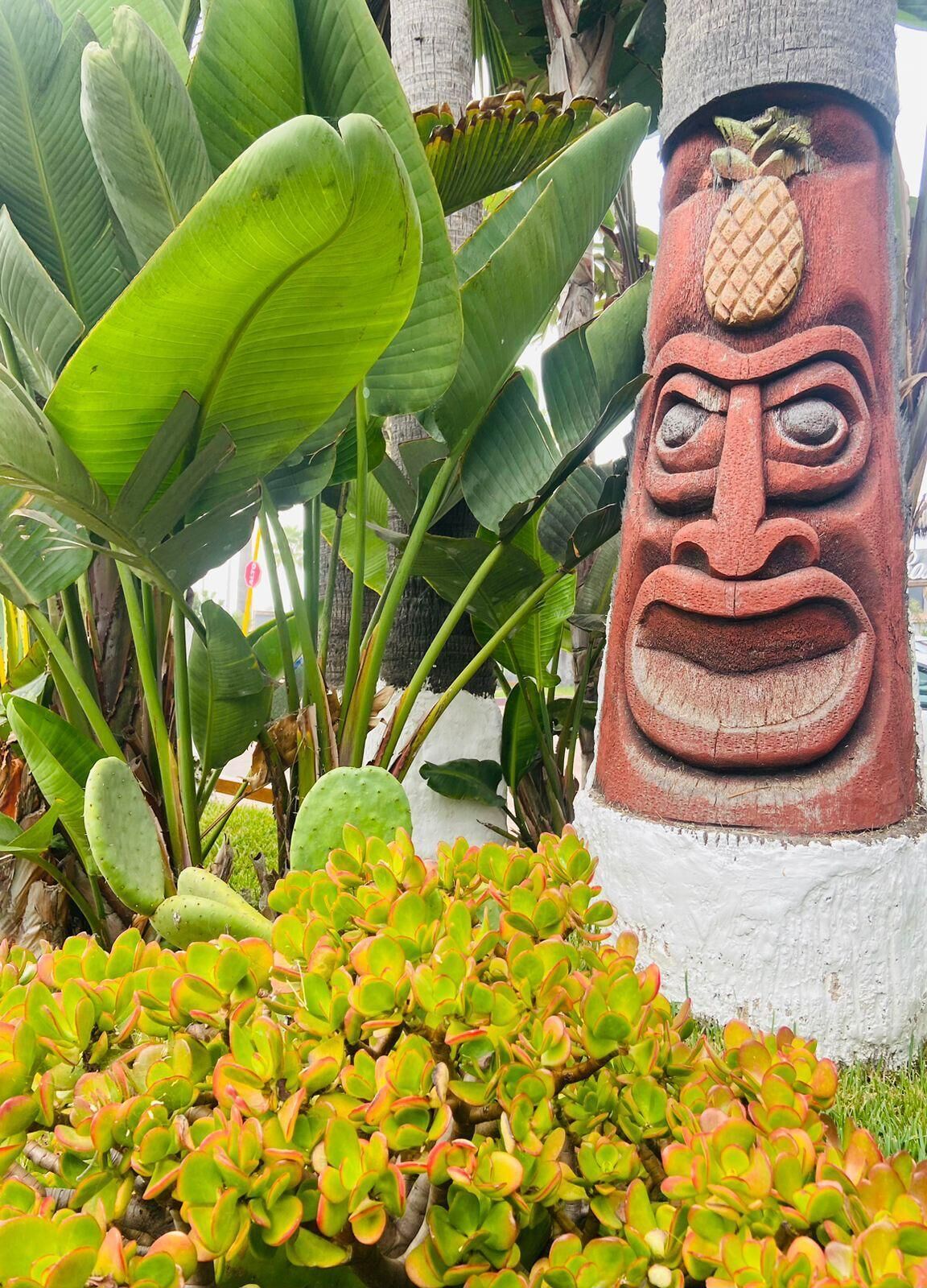Uma estátua tiki cercada por plantas tropicais.