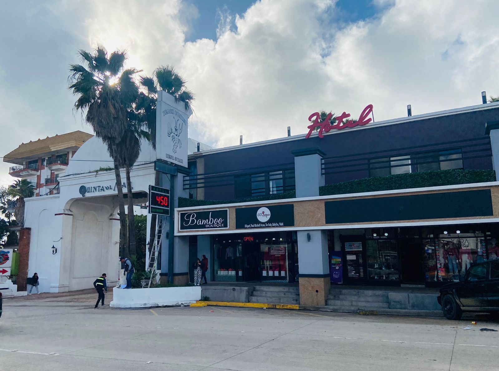 A hotel with a modern facade, a visible entrance, and a sign for 'Bamboo Boutique' across the street.