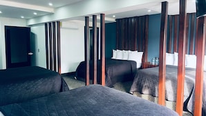 Habitación de hotel con dos camas, un separador de madera, un televisor de pantalla plana y una puerta.