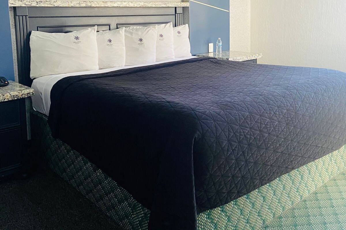 A modern hotel room with a bed, a nightstand, and a headboard.