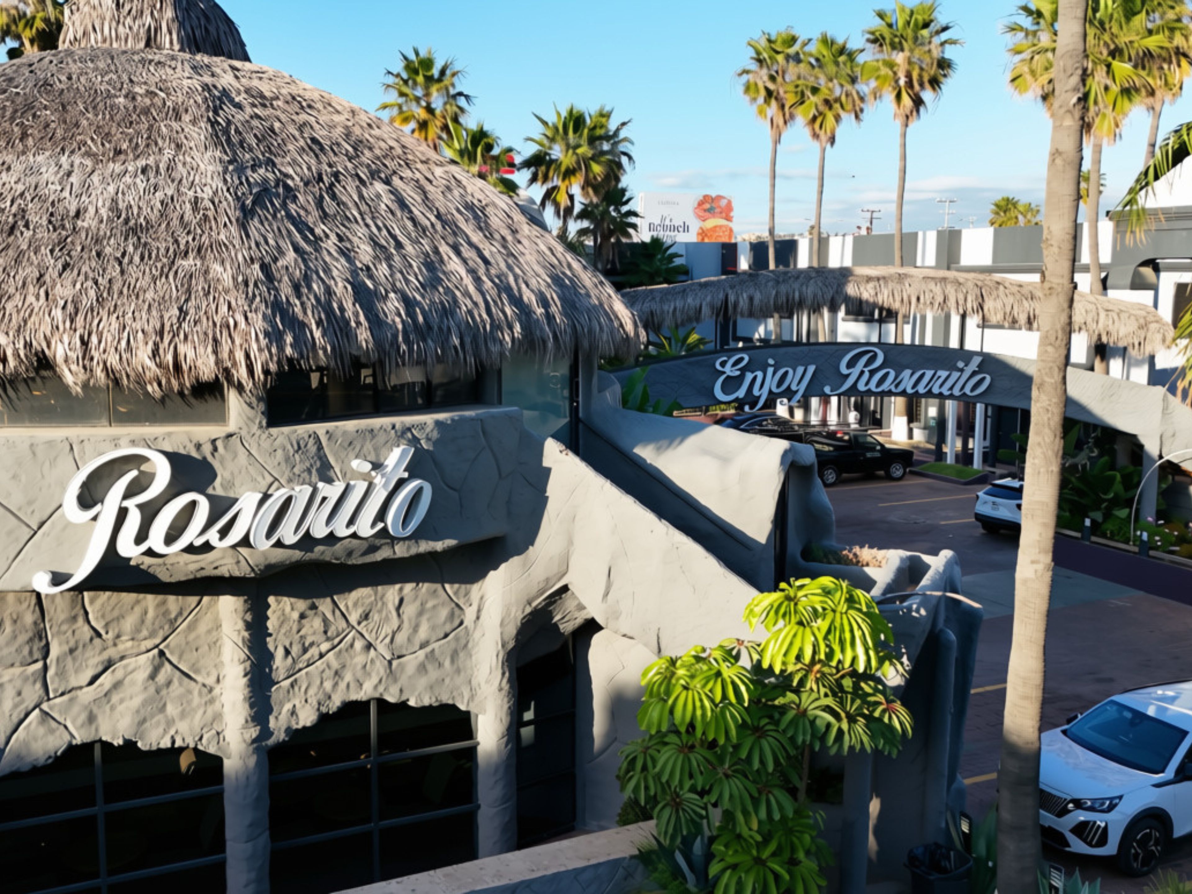 Un bâtiment avec un toit de chaume, sur lequel on peut lire l'inscription « Profitez de Rosarito ».