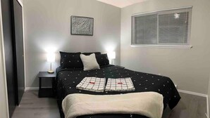 A bedroom with a bed, two bedside lamps, a window with blinds, and a wall-mounted artwork. - 😍GREAT LOCATION 2BD/1BTH UNIT W/ PVT BACKYARD 😍 (Puyallup)