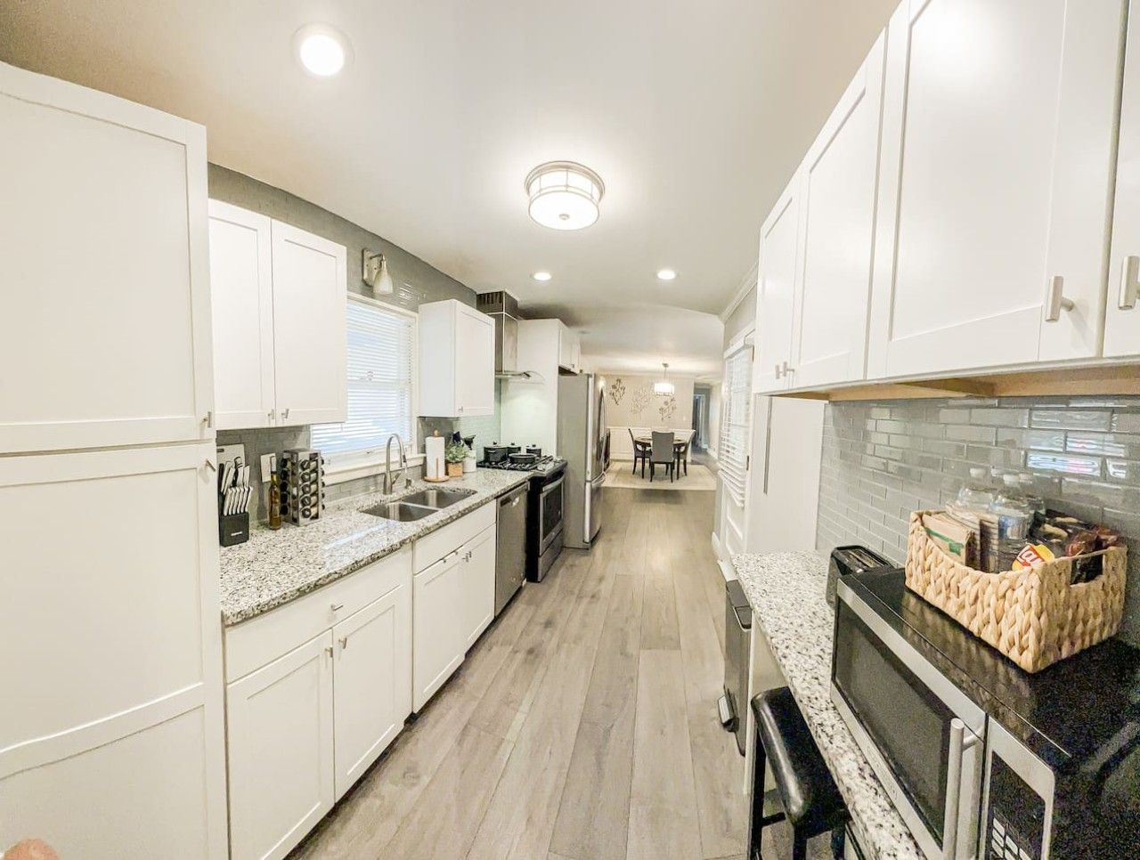 A modern kitchen with white cabinets, granite countertops, and a central island.