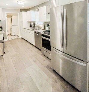 A modern kitchen with stainless steel appliances, white cabinetry, and a patterned floor. - In-Shower Sauna, Fenced Yard W/Deck & BBQ Near ATL (Atlanta)