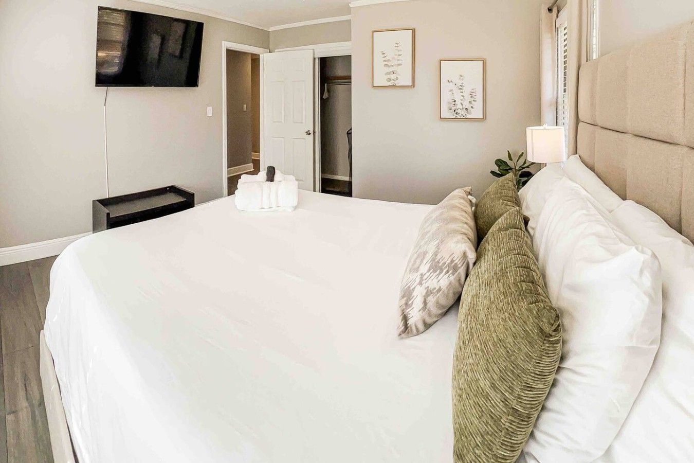 A hotel room with a large bed, a television mounted on the wall, and a door leading to a bathroom.