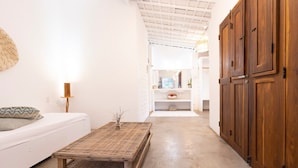 Un interior modern amb un sofà blanc, una taula de centre teixida, armaris de fusta i un paviment de formigó.