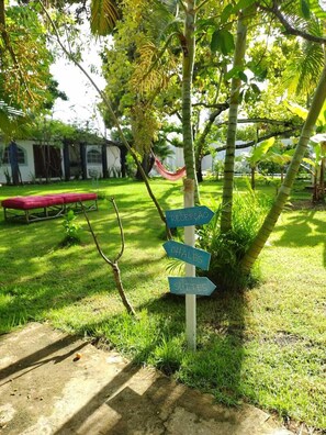 A signpost with directions to 'RECUPERADO', 'CHALÈS', and 'SUITES' in a lush garden setting. - Villa Ostello Pousada (Paripueira)