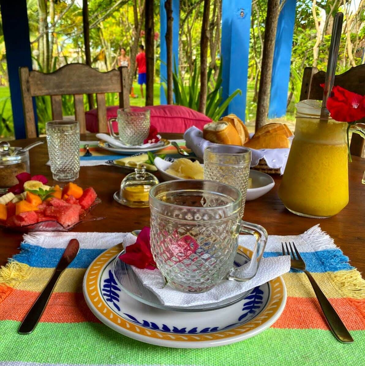 A breakfast setting with a plate of fruit, a glass pitcher, and a cup on a table.