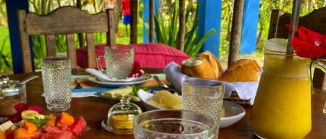 A breakfast setting with a plate of fruit, a glass pitcher, and a cup on a table.