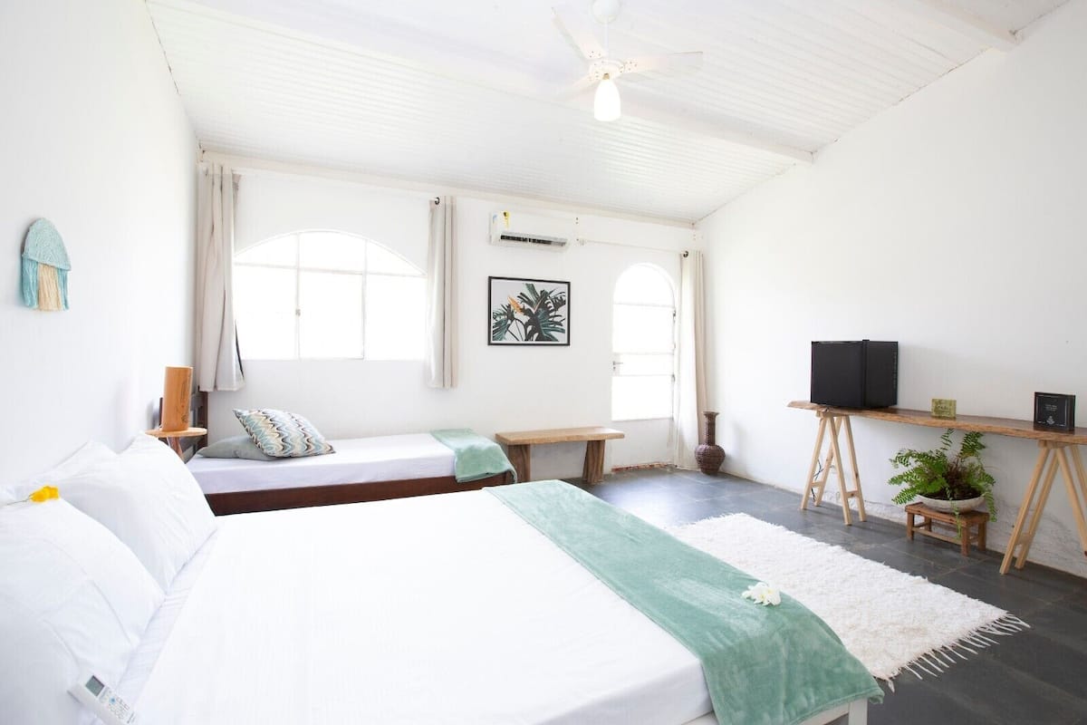 A room with two beds, a desk, a ceiling fan, and a TV.