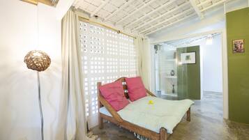 A bedroom with a wooden bed, a white curtain, a woven floor lamp, and a green wall.