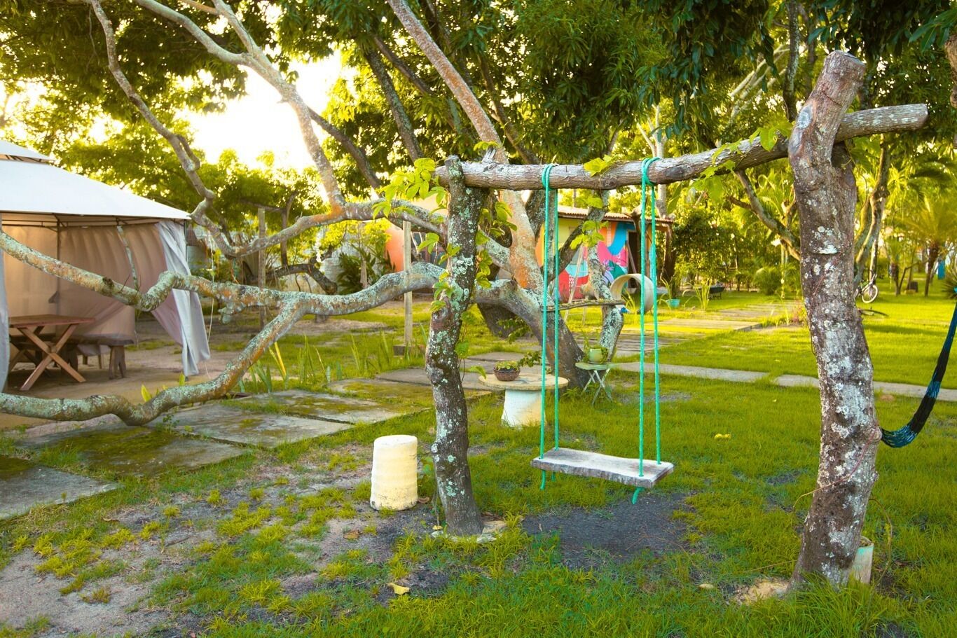 A rustic outdoor area with a swing set, a small shed, and a hammock.