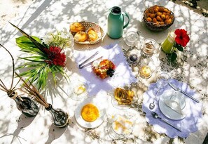 A table set outdoors with various food items, a pitcher, and a flower. - Villa Ostello Pousada (Paripueira)