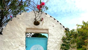 Pared de maó blanc amb una porta blava i un senyal rodó a dalt.