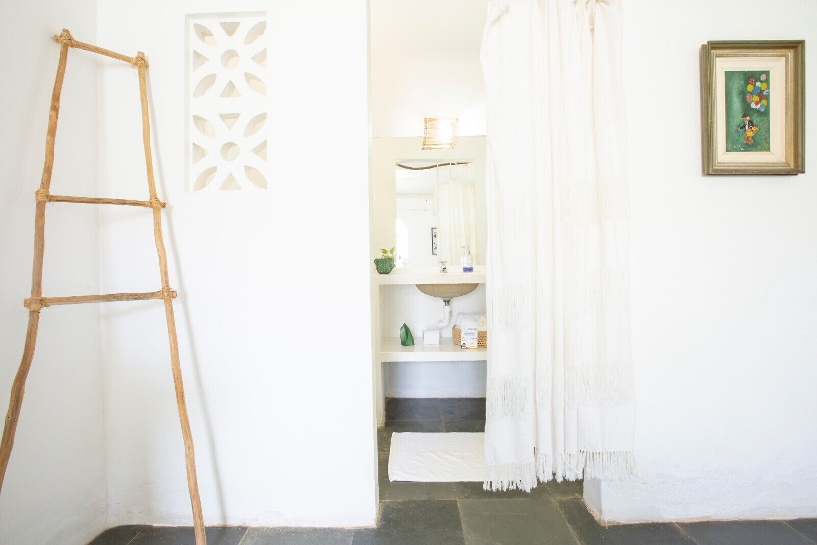 Une salle de bain avec un lavabo blanc, un miroir et un tableau encadré au mur.