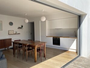 Una cucina moderna con mobili bianchi, un tavolo da pranzo in legno e lampade a sospensione.