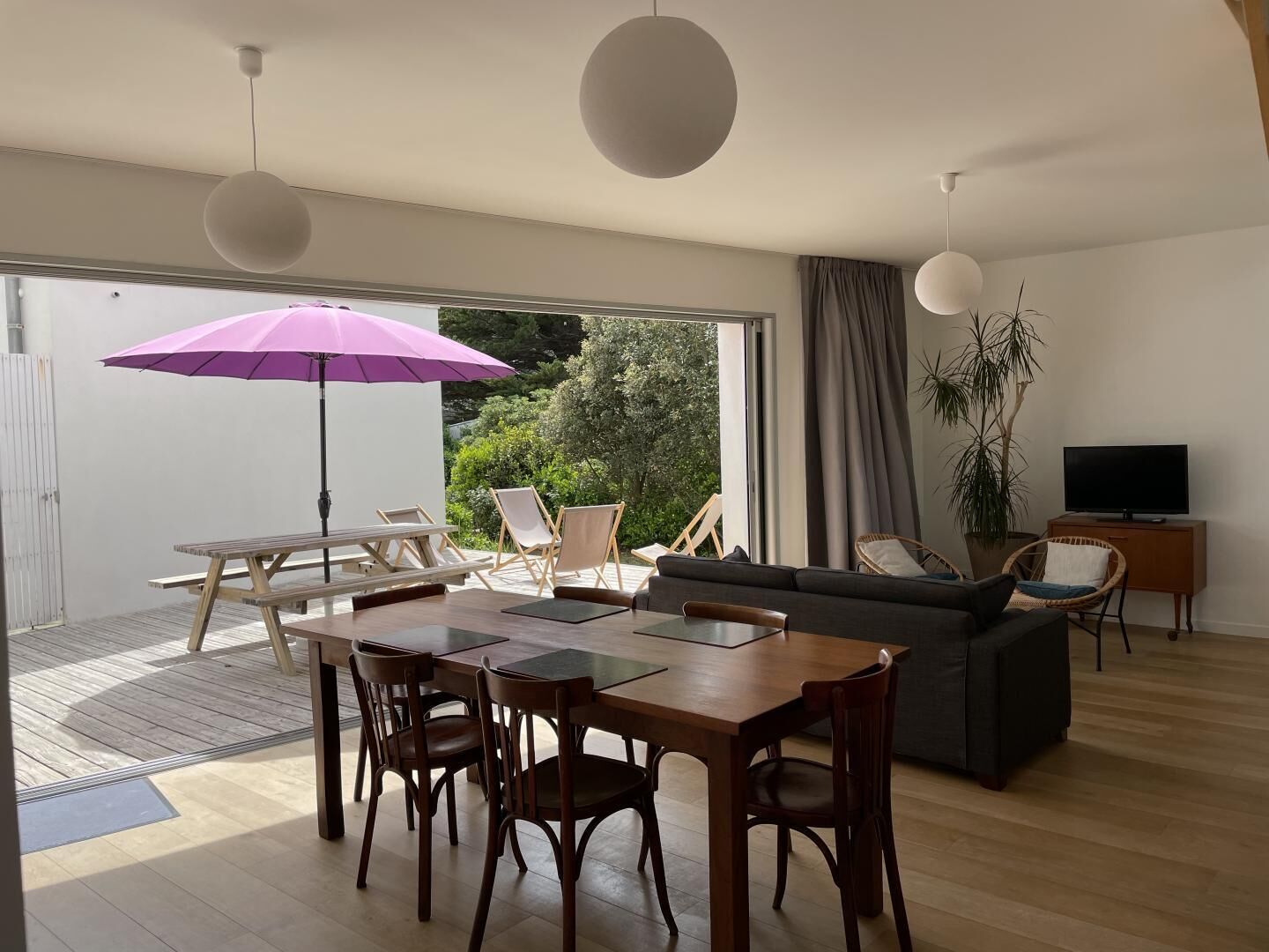 A modern living room with a dining table, chairs, a sofa, and a TV.
