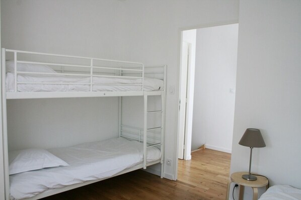 Habitación con literas, una mesita pequeña y una lámpara.