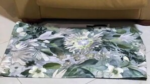 Ein beiges Sofa aus Leder mit einem Teppich mit floralem Muster.