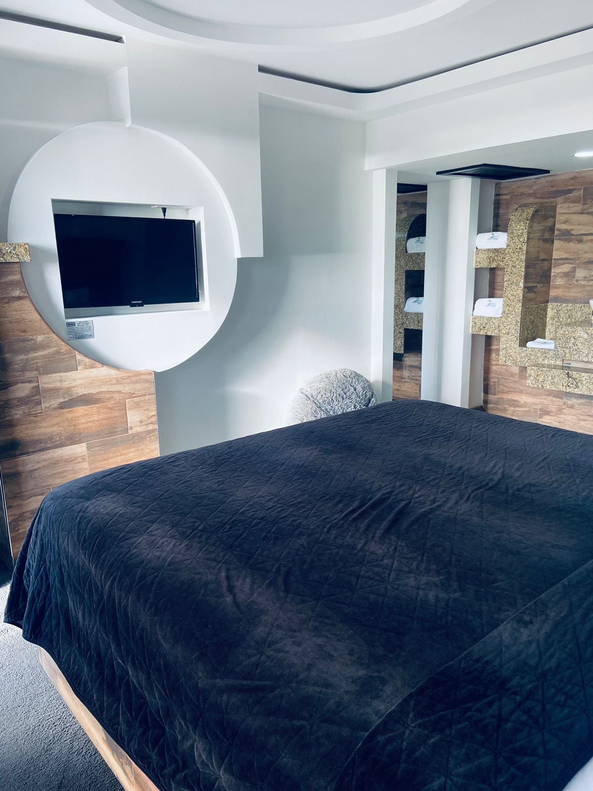 Ein modernes Schlafzimmer mit einem großen Bett, einem wandmontierten Fernseher und einer integrierten Regaleinrichtung.