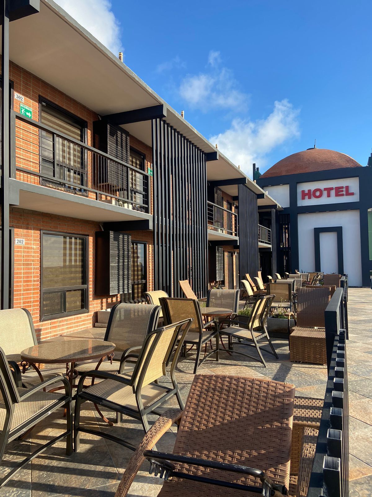 An outdoor seating area with wicker furniture and a clear view of a hotel building in the background.