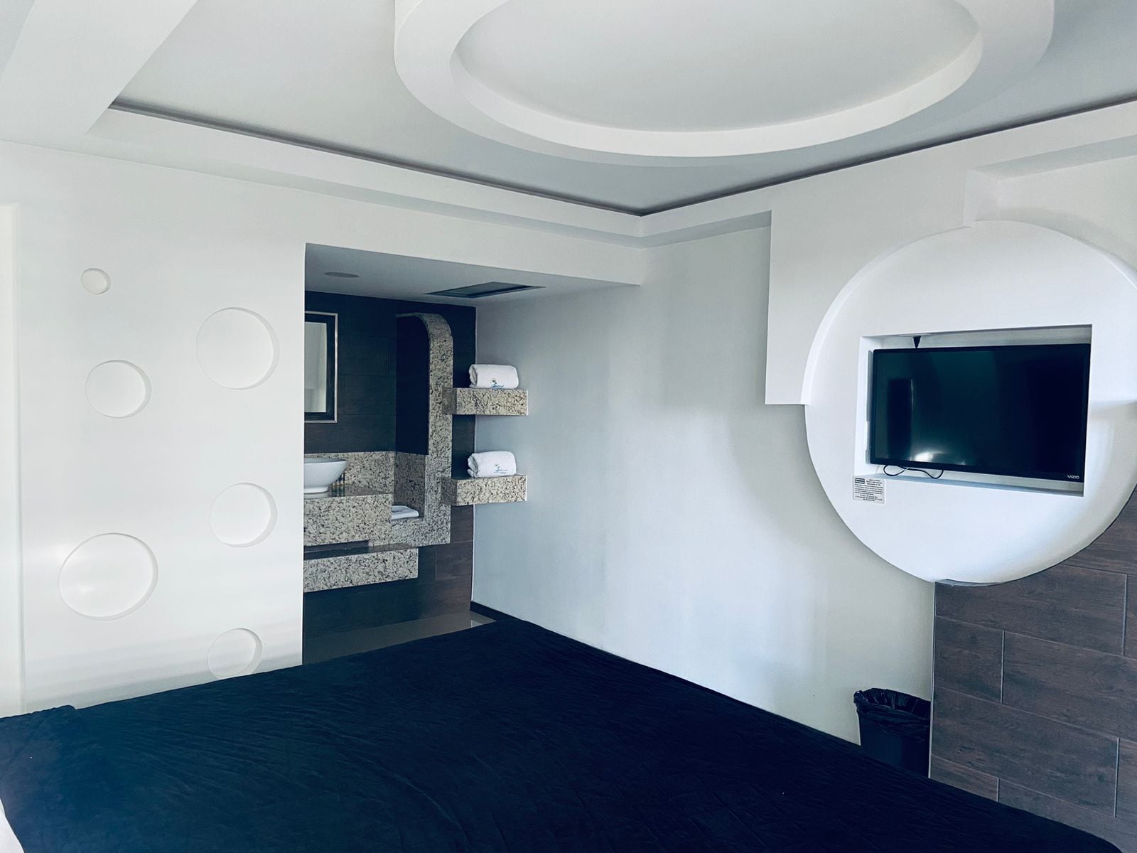 A modern bathroom with a built-in sink, a mirror, and a TV mounted on the wall.