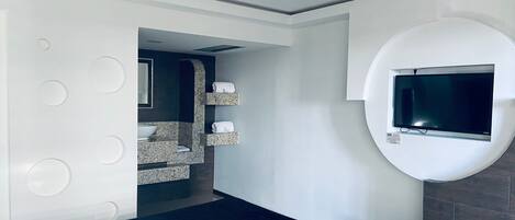 A modern bathroom with a built-in sink, a mirror, and a TV mounted on the wall.
