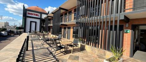 Un hotel con fachada moderna, zona de estar exterior y cielo despejado.