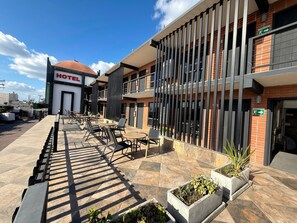 A hotel with a modern exterior, outdoor seating area, and a clear sky. - Hotel Fiesta Rosarito (Playas de Rosarito)