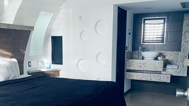 Un dormitorio moderno con una cama grande, un baño con tocador y un diseño de techo único.