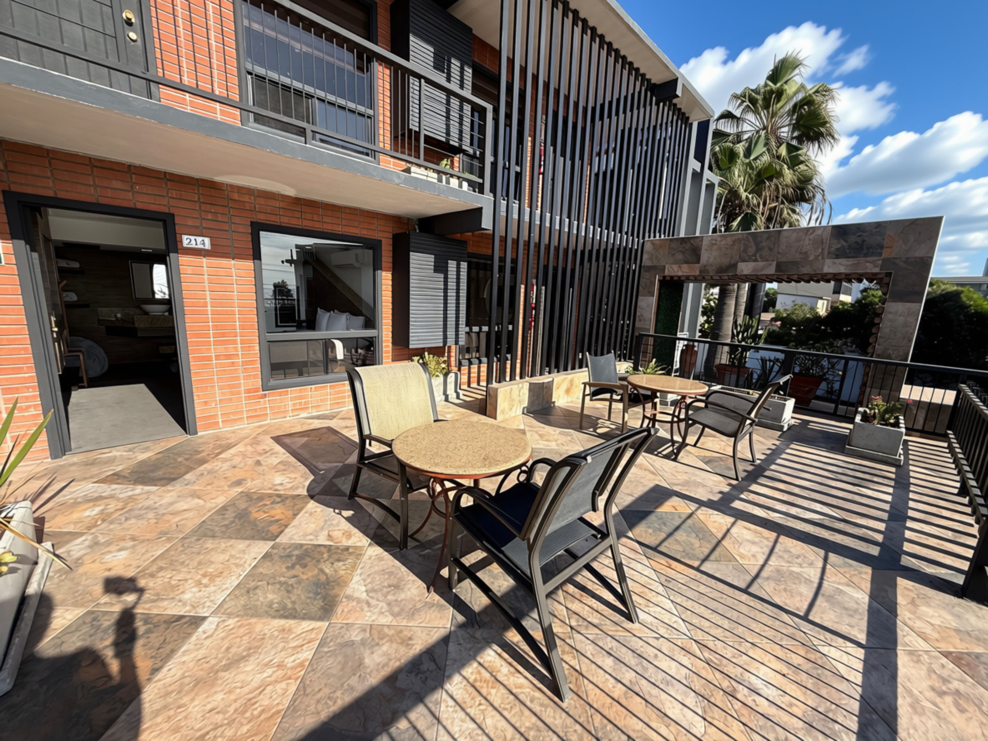 Een modern terras buiten met een eethoek, een zwembad en uitzicht op een palmboom.