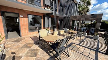 Una moderna terrazza all'aperto con zona pranzo, piscina e vista su una palma.